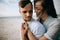 Young woman tenderly hugs her boyfriend on the sea beach. The concept of love