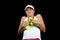 Young woman on a tennis practice. Beginner player holding a racket, learning basic skills. Portrait on black background.