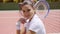 Young Woman with Tennis Racket Sitting on Court