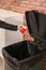 Young woman throwing coffee cup in trash bin indoors, closeup.