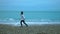 Young woman throwing pebbles into ocean, foamy waves splashing ashore in slow-mo