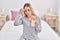 Young woman tired drinking cup of coffee sitting on bed at bedroom