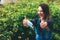 A young woman took off a blue medical mask and rejoices at the end of quarantine, shows with her hands a super sign in the park.