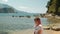 Young woman tosses pineapple standing on beach in summer day.