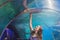 A young woman touches a stingray fish in an oceanarium tunnel