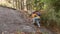 Young woman tourist with backpack hiking alone climbing a rock in the forest