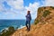 Young woman tourist at Cape Cabo da Roca standing on the rocky edge of the cliff. The waves of the ocean break on the rocks at the