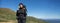 Young woman tourist hiker with a large backpack stands on the top of the mountain. Baner.