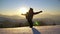 Young woman tourist jumping in deep snow. In the background, the sun sets over the mountain. Behind the back of a