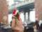 A young woman tourist in a Santa Claus hat walks during a snowfall in New York City on Christmas Eve. Manhattan Bridge and