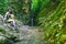 Young woman tourist sits in a beautiful gorge in front of mountain stream