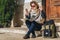 Young woman tourist sits on street on steps, looking for path on map, next to her backpack. Tourism, travel, vacation.