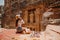 Young woman tourist sitting on a cliff after reaching the top, Al Khazneh in the ancient city of Petra, Jordan, UNESCO World