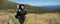 young woman tourist stands on a mountain slope. Large travel backpack. Baner