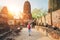Young woman tourist in a straw hat and white clothes walking with light city backpack through Ayutthaya Wat Phra Ram ancient ruins