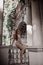 Young woman tourist in summer dress is sitting on ancient balustrade of old palace terrace looking at classic column