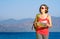 Young woman tourist walks on the seashore reading the map.