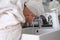 Young woman with towel on head washing face under tap in bathroom