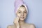 A young woman with a towel on her head cleans her face with a cotton pad. Facial cleansing, cosmetics removal, skin care. Spa