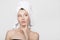 Young woman with a towel on her head looks up. A hand near her face. Skin and body care concept