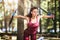 Young woman in tracksuit doing exercises in the park with fitness straps attached to a tree. The athlete trains the chest muscles