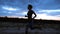 A young woman in a tracksuit jogging along the sand pier of the cargo port, in the twilight of the morning dawn. View