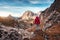 Young woman on the trail looking on high mountain peak at sunset