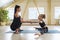 Young woman trainer, engaged personally with a little girl, helping to perform an exercise to stretch the muscles