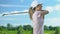 Young woman training to play golf on course at sunny day, happy with good hit