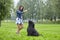 Young woman trains black briard during dog walking on open air.