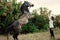 Young woman trains grey horse in pasture