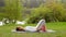 Young woman trains her hands while lying on a yoga mat at a river bank