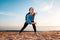 A young woman trains on the sandy beach of the ocean. Outdoor. Sports and healthy lifestyle. Bottom view