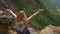 Young woman-traveler with a backpack in the mountains. She is looking at the majestic valley down there. Travel concept