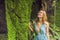 Young woman traveler in a Balinese garden overgrown with moss. Travel to Bali concept