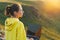 Young woman traveler freelancer in yellow hoodie with opened laptop on the beautiful view background