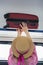 Young woman traveler in hat puts the suitcase on the top shelf in the train