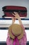 Young woman traveler in hat puts the suitcase on the top shelf in the train