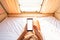 Young woman traveler laying in camper van and using smart phone while road trip traveling on vacation