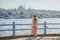 Young woman traveler in pinc dress enjoying great view of the Bosphorus and lots of seagulls in Istanbul