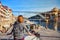 Young woman traveler standing back enjoying beautiful cityscape view on Douro river, bridge and boats during the morning light in