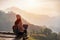 Young woman traveler working online using laptop and enjoying the beautiful nature landscape with mountain view