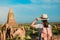 Young woman traveling backpacker with hat, Asian traveler standing on Pagoda and looking Beautiful ancient temples