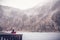 A young woman traveling in the mountains in winter, drinking hot tea against the backdrop of a frozen lake, the Alps