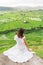 A young woman traveller wearing white dress sitting and looking to rice paddy in Bali island, Indonesia