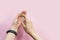 Young woman treats her hands with an antiseptic on a pink background. Place for text