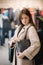 Young woman trying on black bag. Woman in boutique