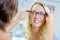 Young woman trying on glasses in optical store