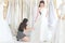 An young woman is trying wedding dress in studio, designer is as