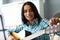 Young woman tunes guitar for music practice